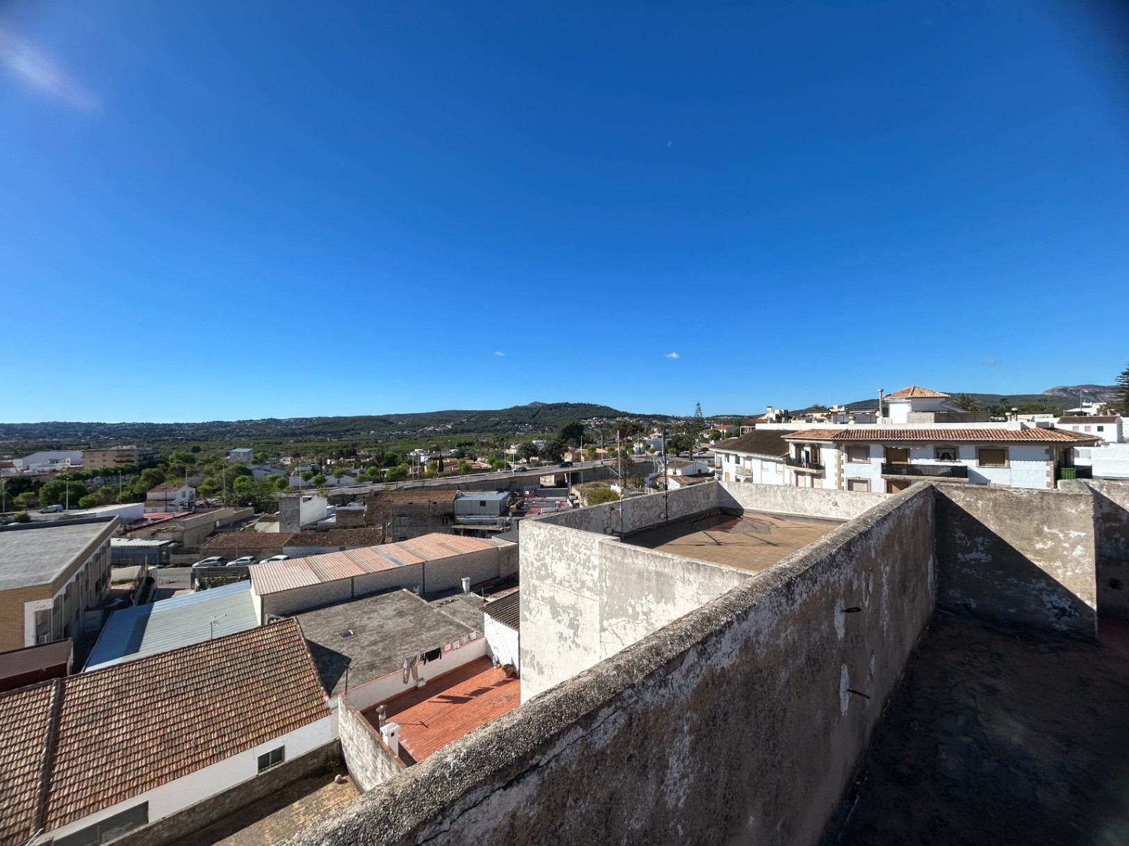 Vue surélevée depuis la terrasse de toit commune, offrant un panorama sur le paysage urbain de Jávea et les montagnes au loin.