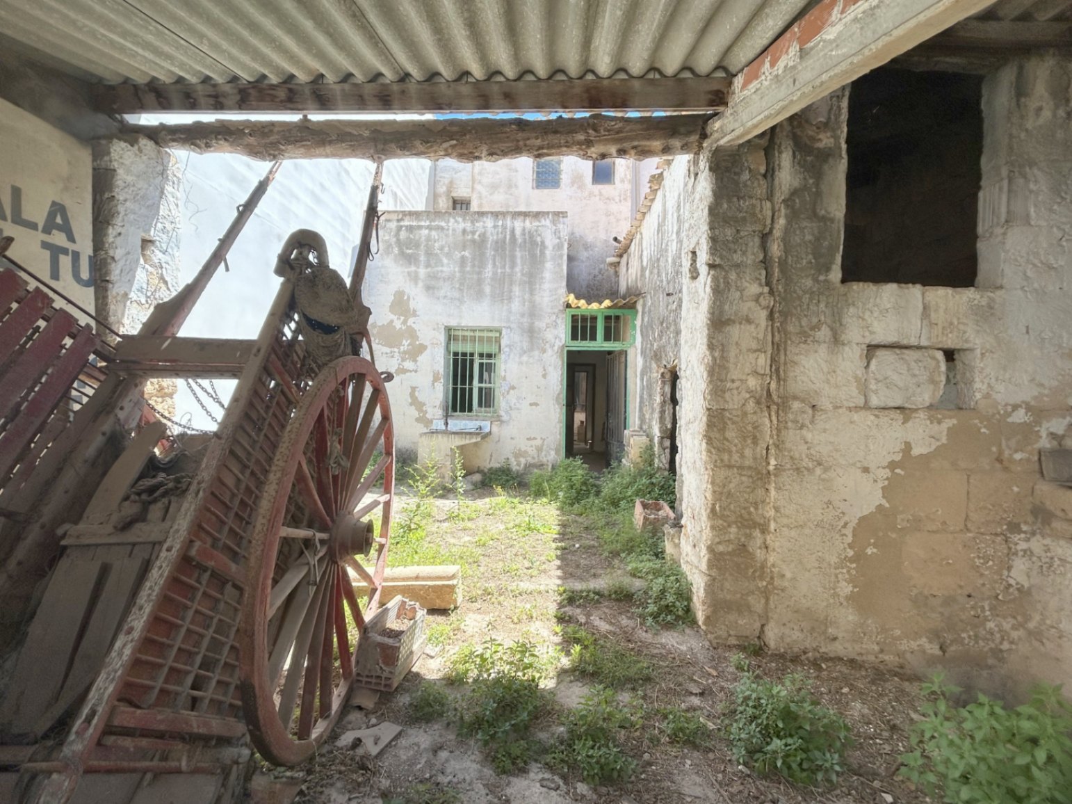 Cour arrière avec une ancienne charrette en bois et des murs en pierre d'origine. Espace extérieur avec accès indépendant et fort potentiel de rénovation.