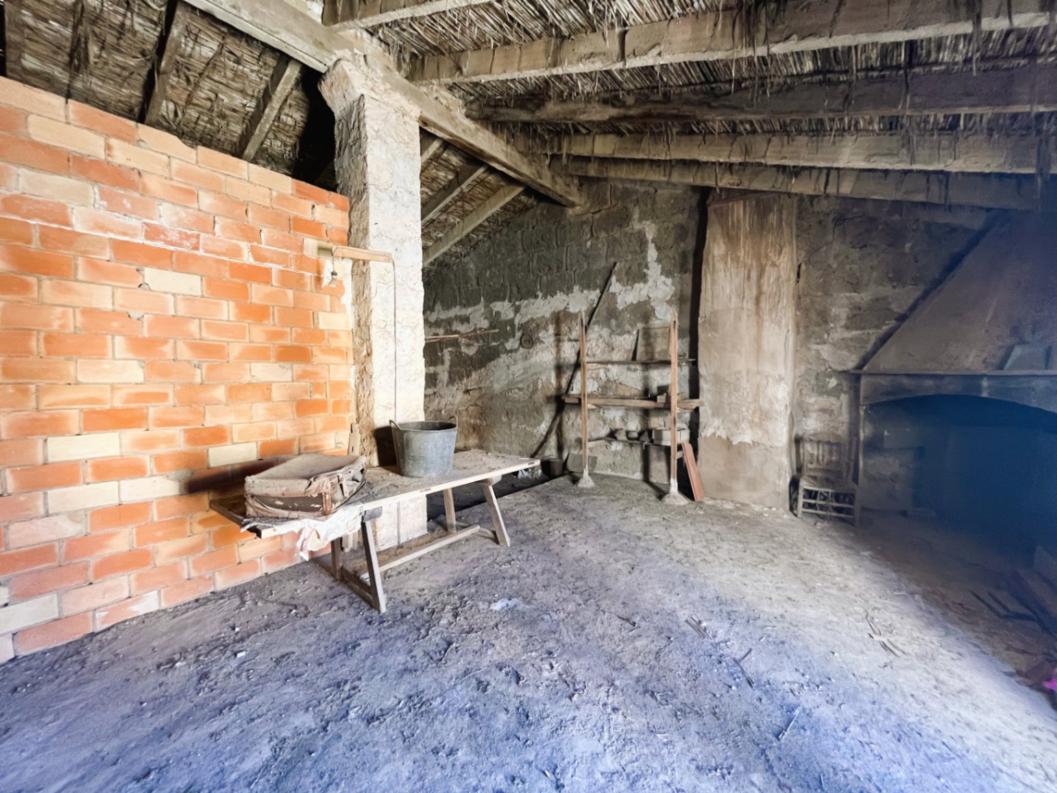 Grenier ouvert avec plafonds en roseaux et poutres en bois d'origine. Espace rustique comprenant une cheminée en pierre et un fort potentiel de rénovation.