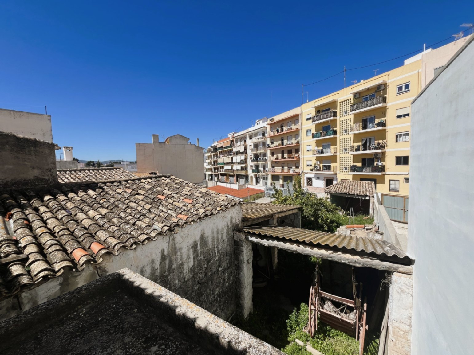 Vue surélevée sur la cour arrière et les toits traditionnels en tuiles, illustrant l'intégration de la propriété dans le tissu urbain de Jávea.