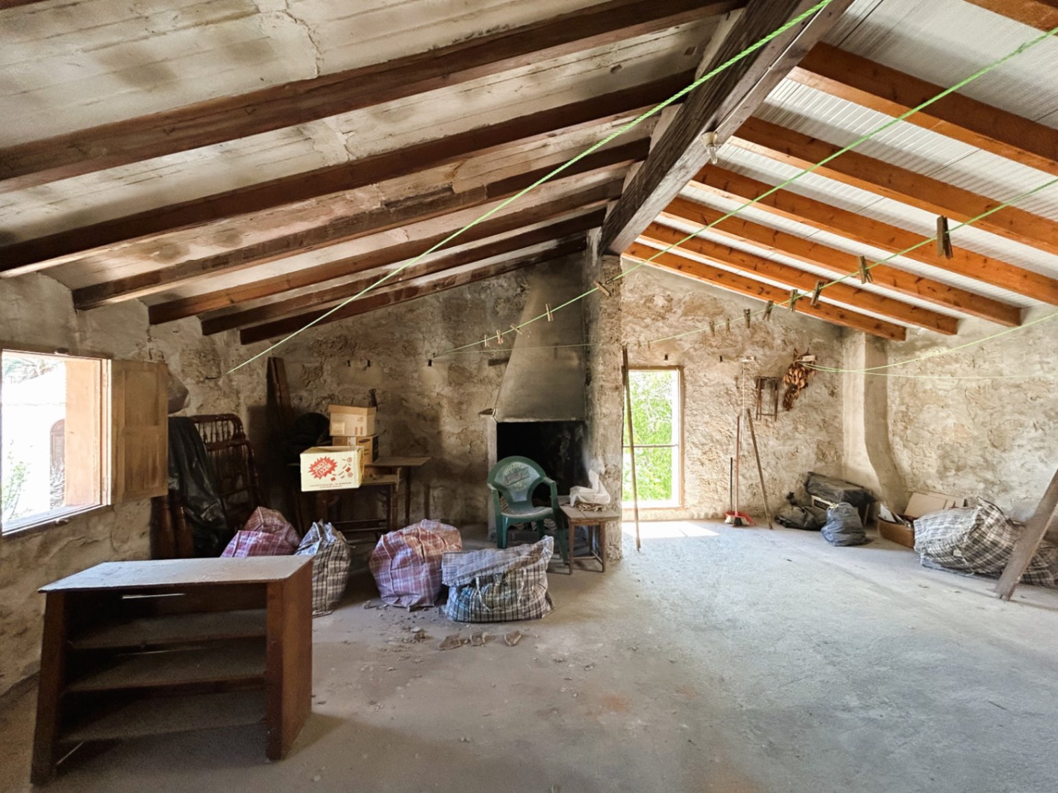 Grenier spacieux avec poutres en bois apparentes, murs en pierre d'origine et cheminée, offrant un fort potentiel de rénovation au cœur de la vieille ville.