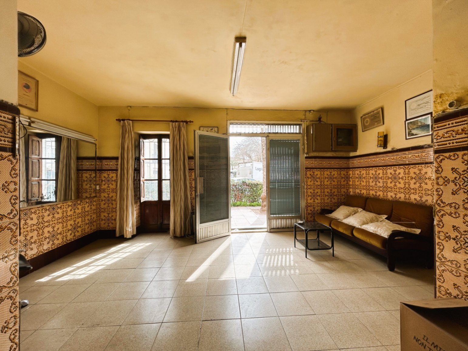 Hall d'entrée spacieux avec des plinthes en carreaux de faïence traditionnels, un sol en céramique et un accès direct vers l'extérieur par de grandes ouvertures lumineuses.