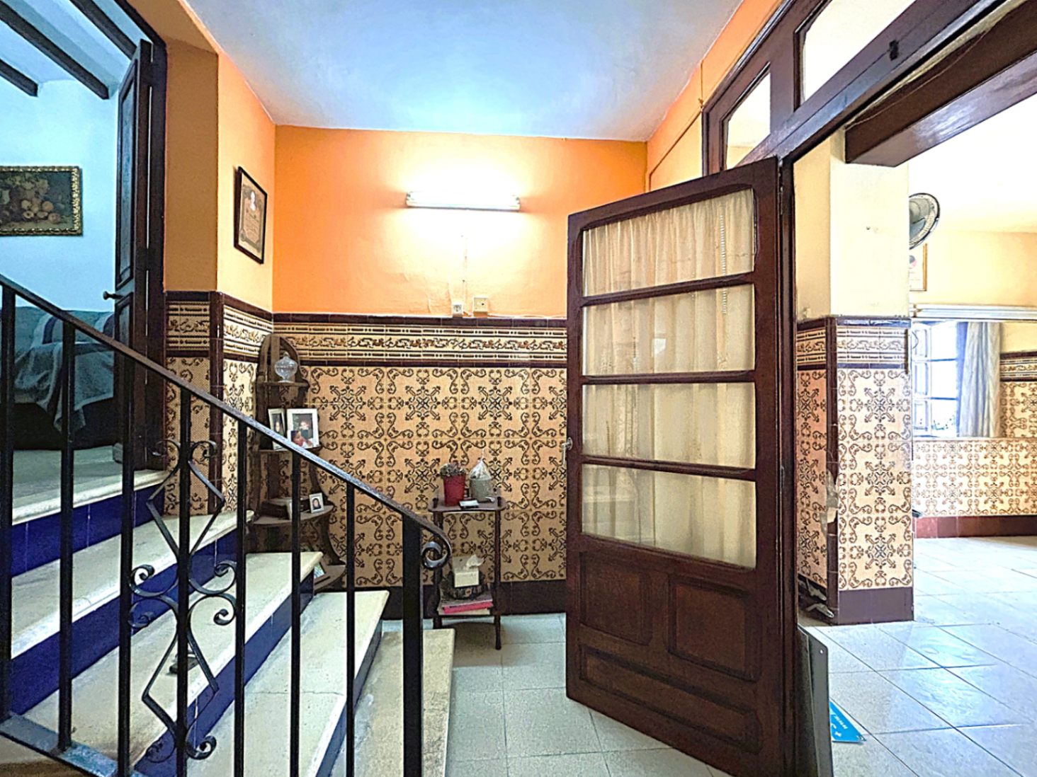 Hall d'entrée traditionnel avec soubassements en azulejos, escalier en pierre aux contremarches bleues et rampe en fer forgé d'époque à Jávea.