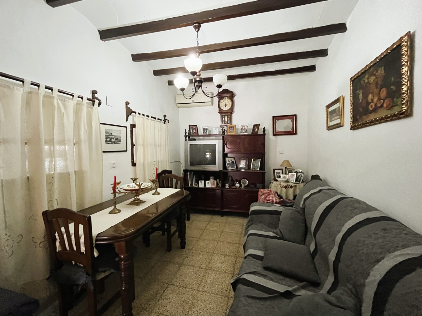 Salon-salle à manger traditionnel avec poutres apparentes en bois sombre, sol en terrazzo et mobilier classique dans la vieille ville de Jávea.