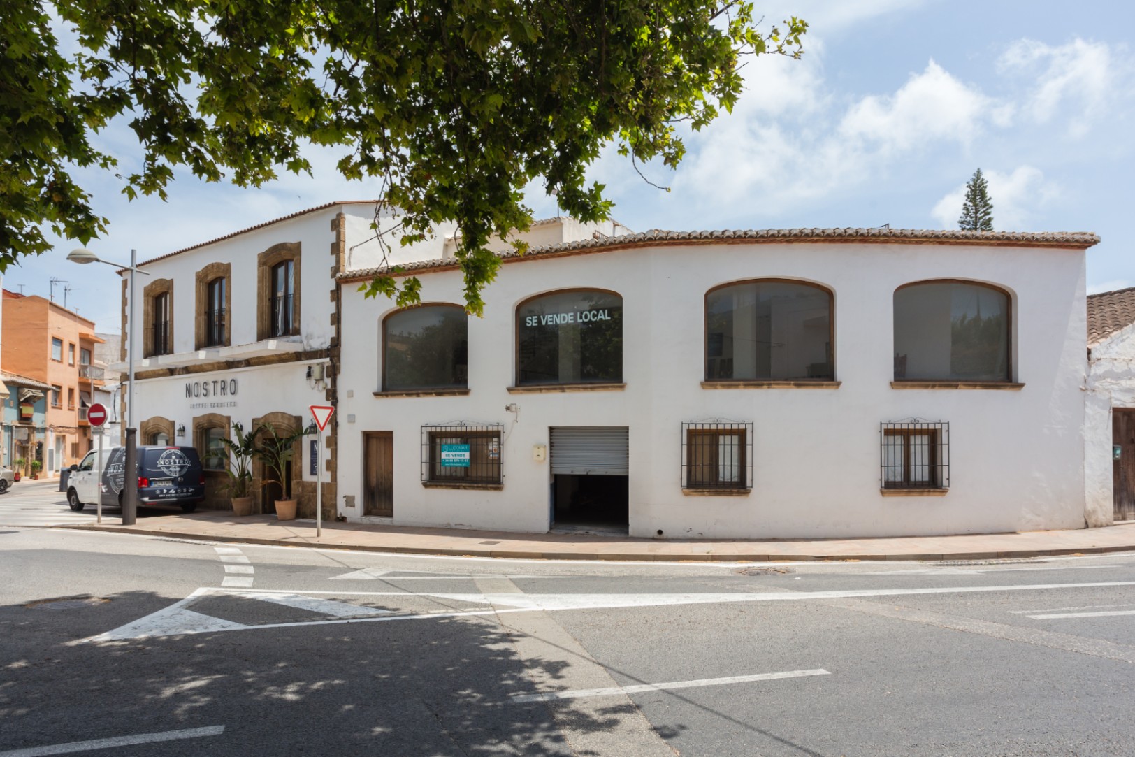 Façade d'angle à Jávea avec encadrements en pierre de tosca, grandes fenêtres à l'étage et structure méditerranéenne traditionnelle sur deux niveaux.