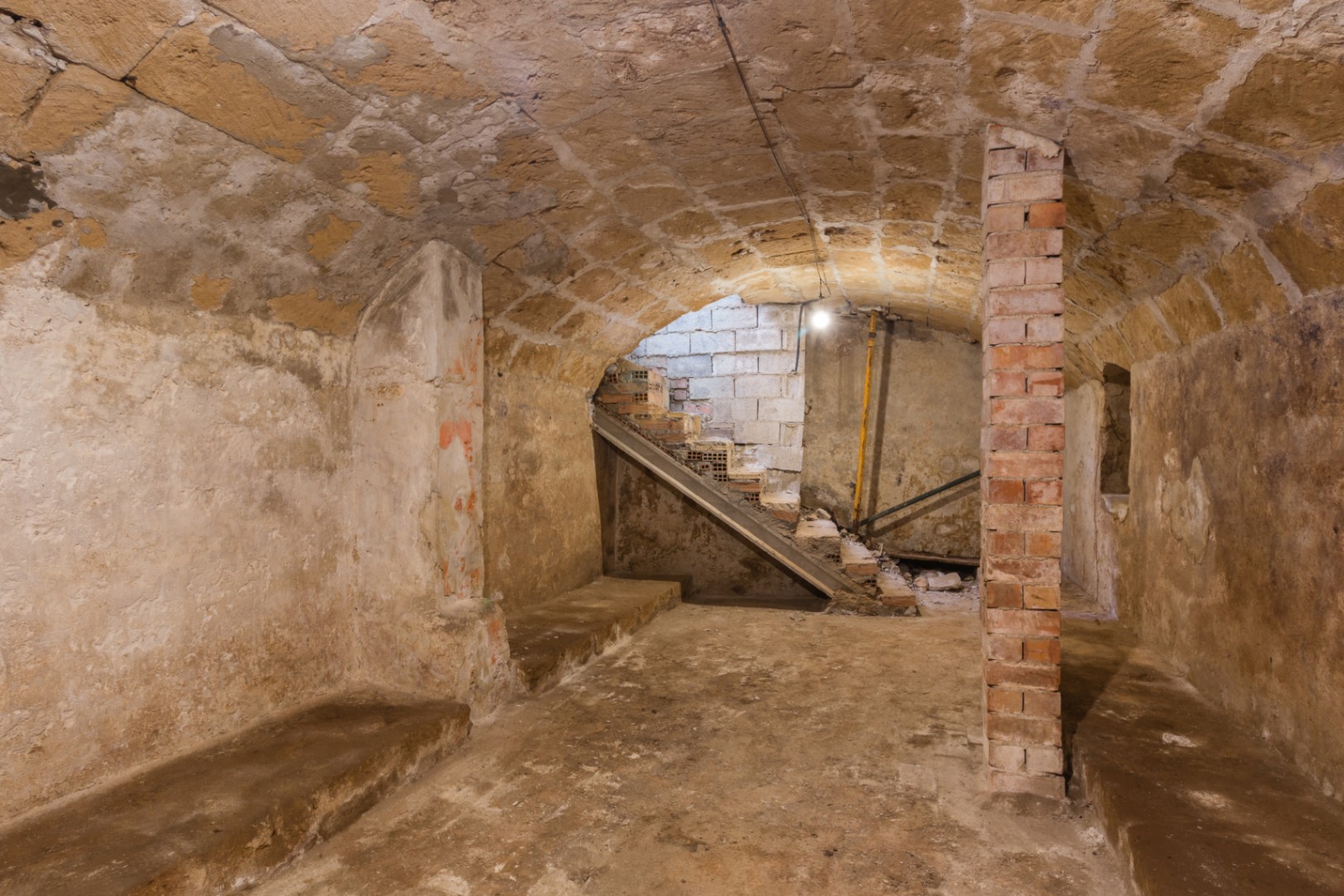 Sous-sol avec plafonds voûtés en pierre de tosca d'origine et piliers en briques. Espace brut avec accès aux escaliers, idéal pour une cave à vin ou un salon.