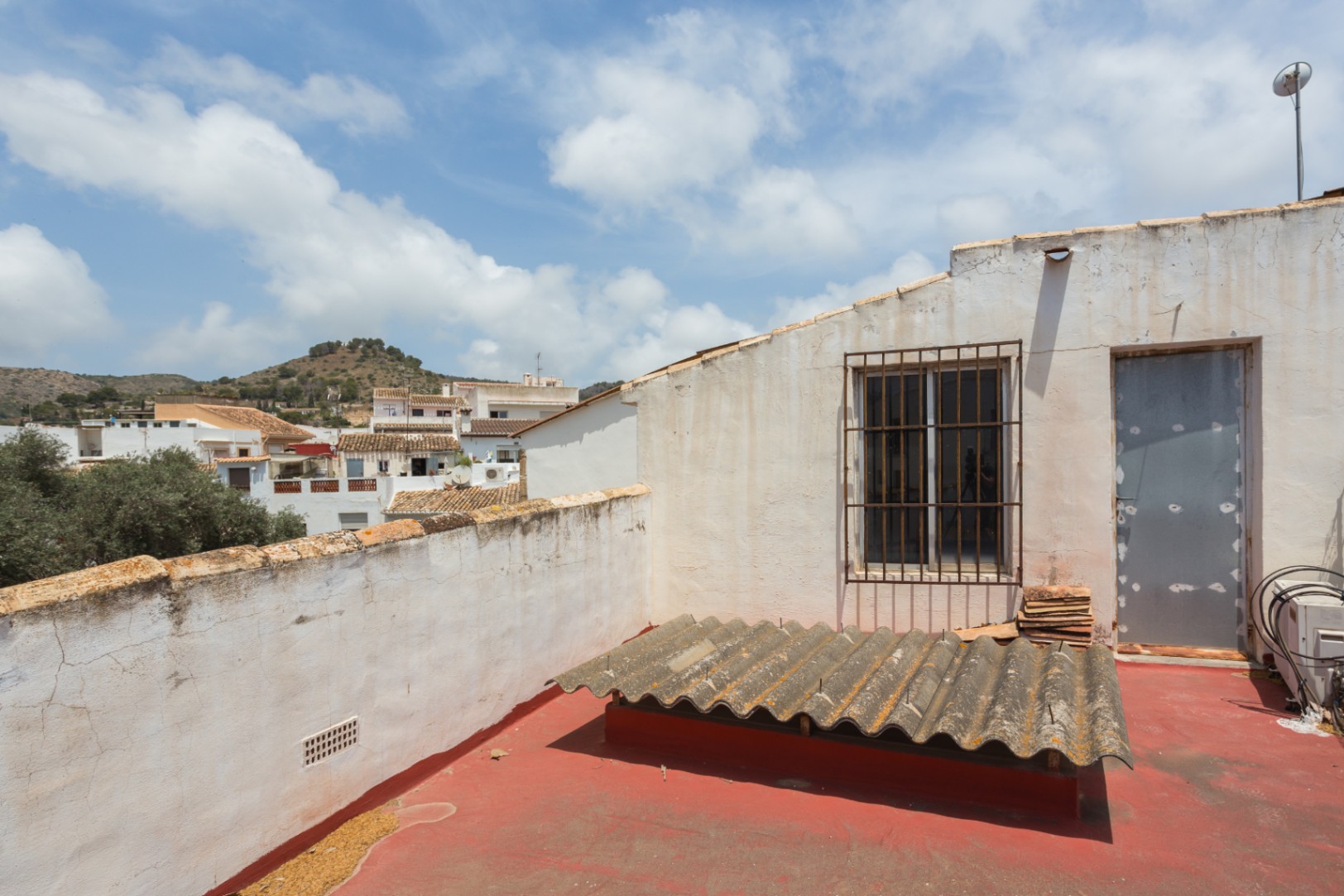 Terrasse sur le toit avec sol peint en rouge offrant une vue dégagée sur le paysage urbain et les collines environnantes de Jávea.