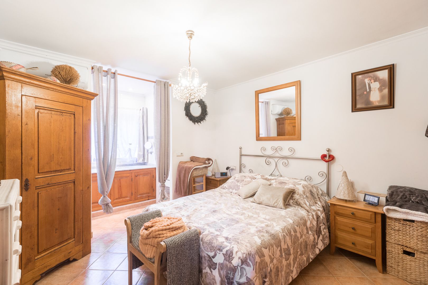 Chambre avec sol en céramique, armoire en bois classique et tête de lit en fer forgé. Comprend la climatisation, un lustre en cristal et une grande fenêtre.