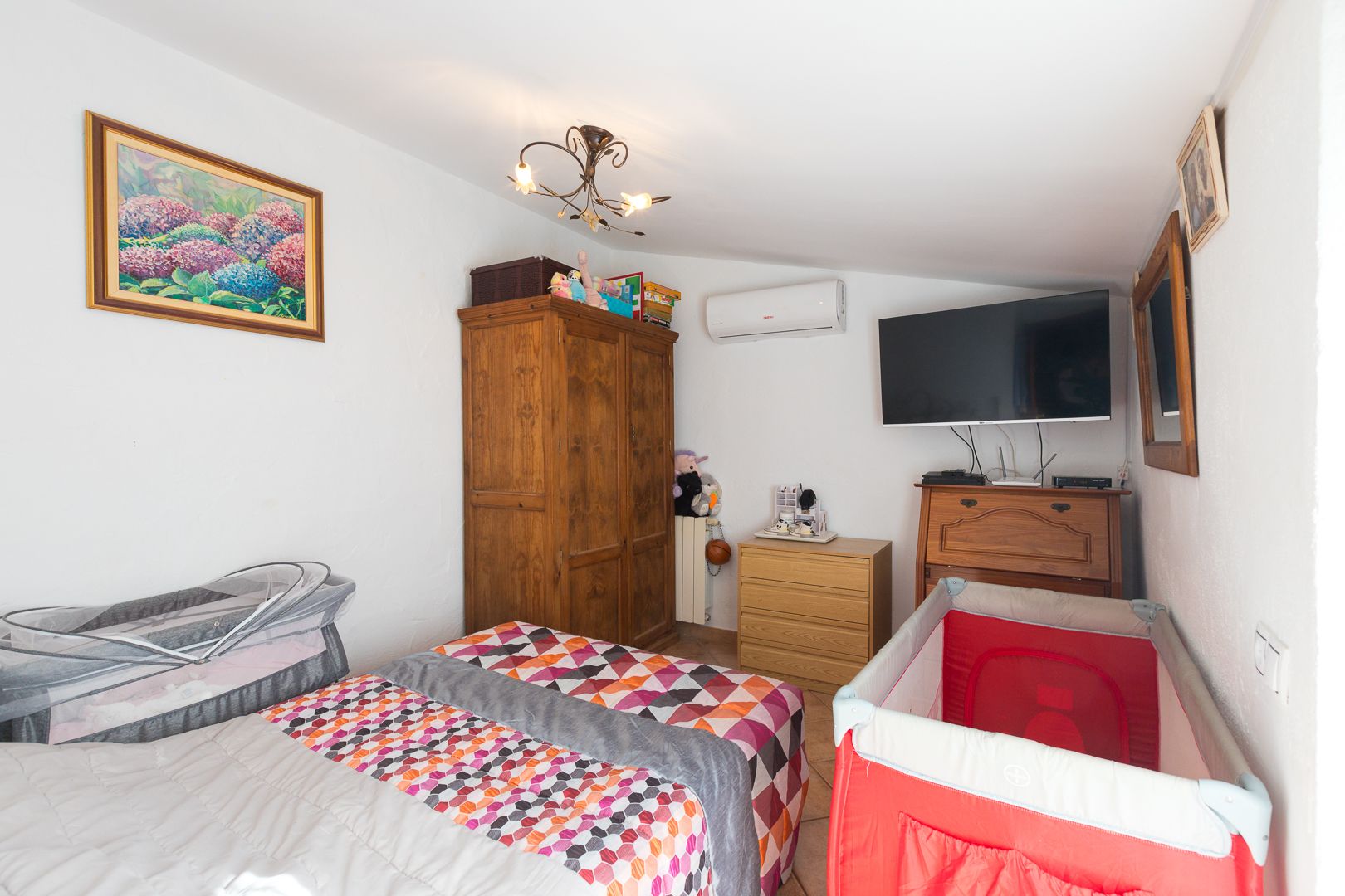Chambre lumineuse avec plafonds rampants, climatisation réversible, armoire en bois massif et espace optimisé pour l'accueil de jeunes enfants.