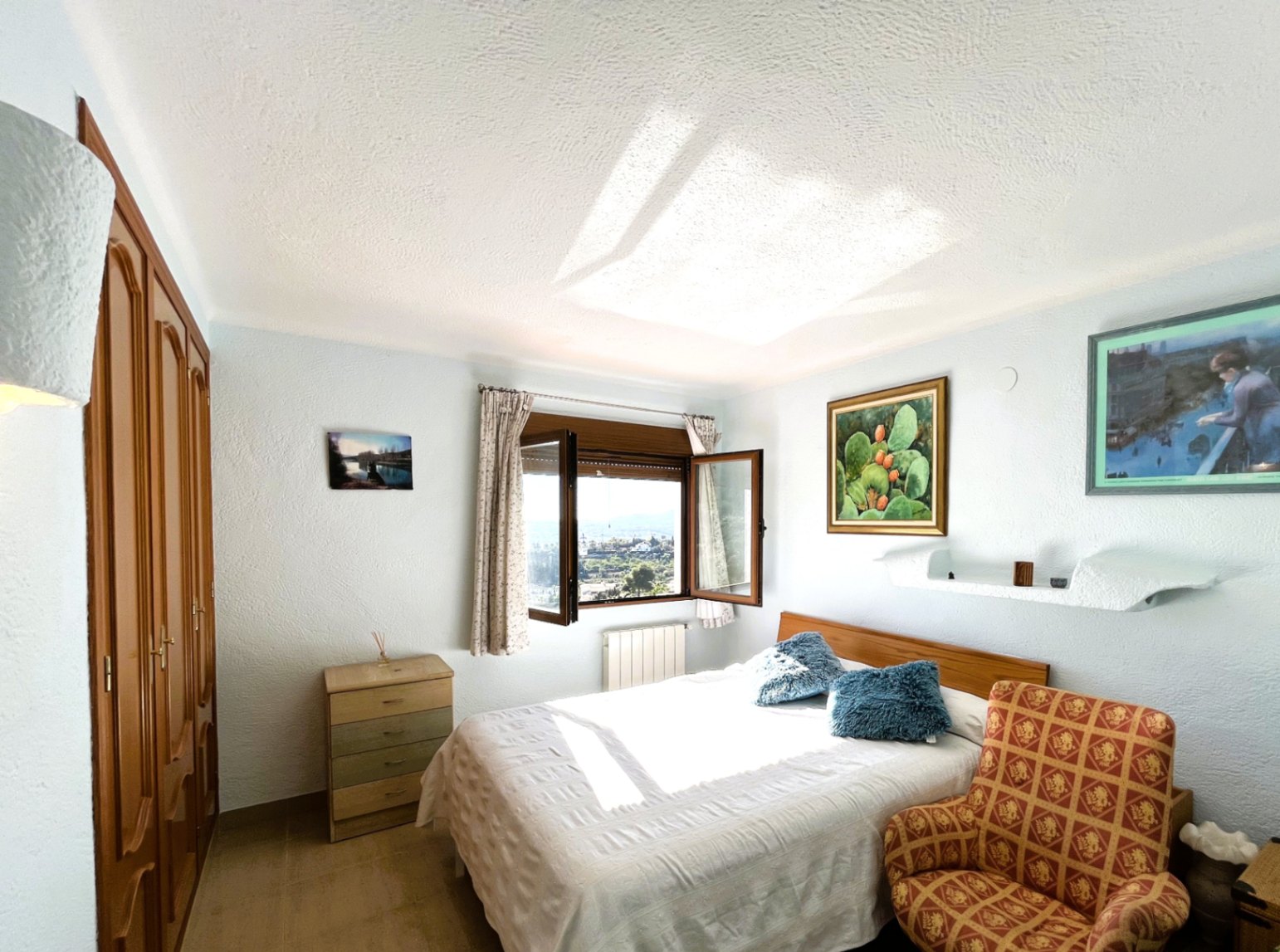 Chambre avec placards intégrés en bois et lit double, dotée d'une fenêtre offrant une lumière naturelle et des vues dégagées sur la vallée.