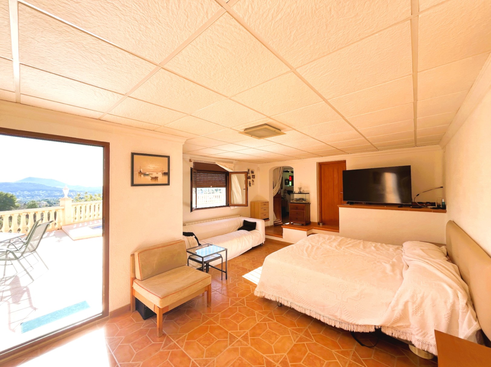 Espace de vie indépendant au niveau inférieur avec coin nuit, sol en grès et accès direct à la terrasse offrant une vue panoramique dégagée.