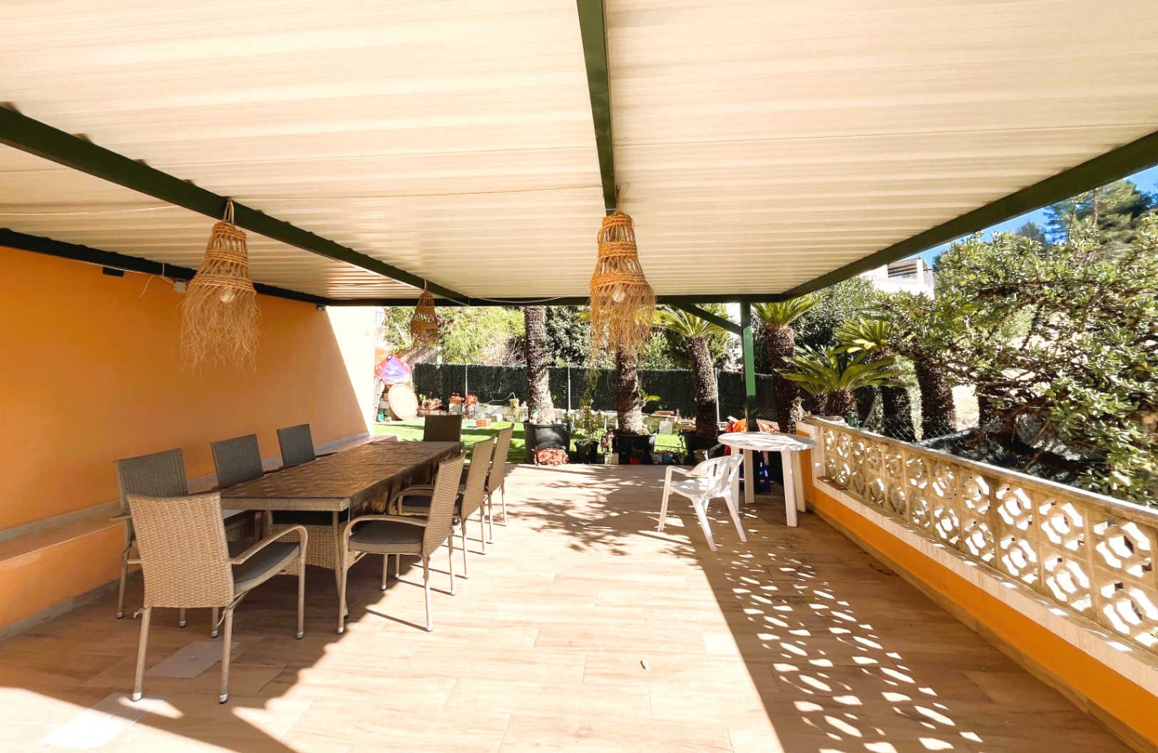 Terrasse couverte avec espace repas extérieur, suspensions en osier et balustrade décorative donnant sur le jardin méditerranéen.