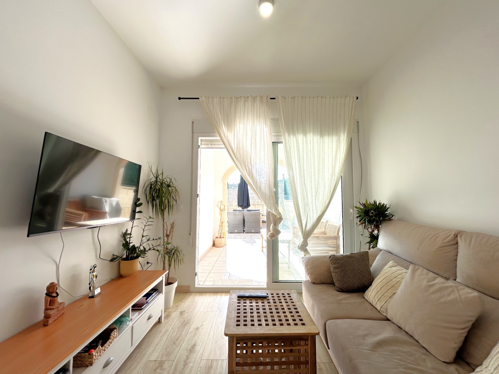 Salon lumineux avec accès direct à la terrasse privée, doté d'un sol imitation bois et de grandes baies vitrées.