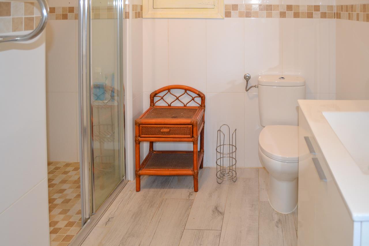 Salle de bains fonctionnelle avec douche à l'italienne, meuble d'appoint en bambou, sol en grès cérame effet bois et frise décorative en mosaïque.