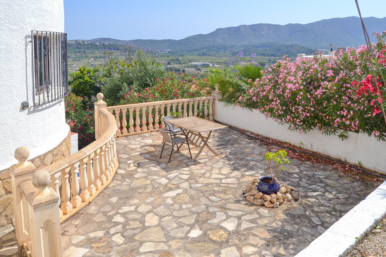 Terrasse extérieure avec revêtement en pierre naturelle, balustrade classique et vue dégagée sur la vallée et les montagnes environnantes.
