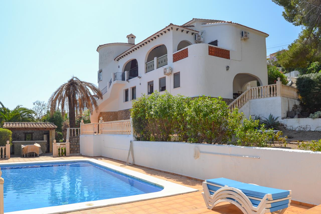 Vue extérieure de la villa avec piscine privée, terrasses ensoleillées et architecture méditerranéenne traditionnelle aux arcades élégantes.