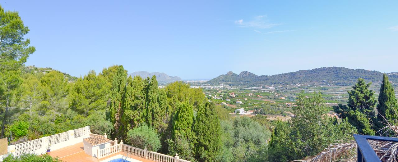 Vue panoramique sur la vallée et la mer Méditerranée depuis la terrasse supérieure, surplombant la piscine et ses balustrades en pierre.