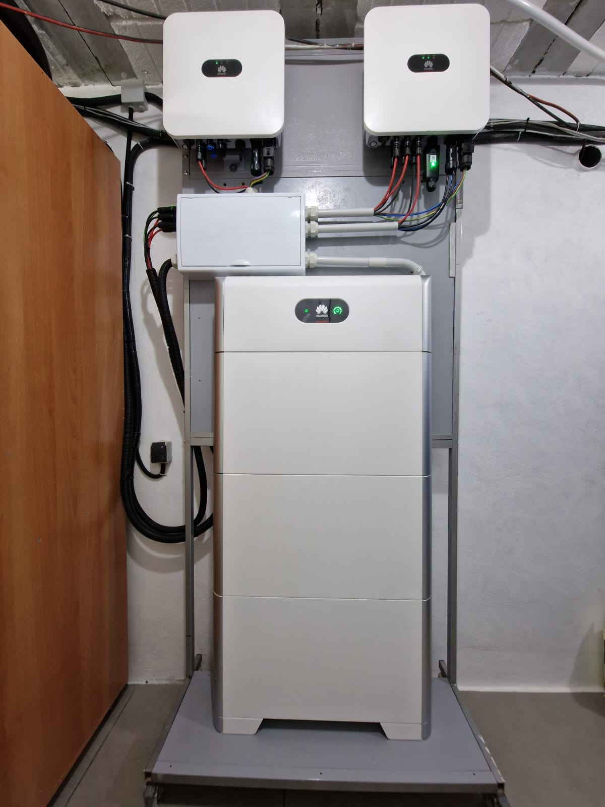 Installation de batterie et de régulateurs solaires Huawei dans un local technique. Câblage apparent.