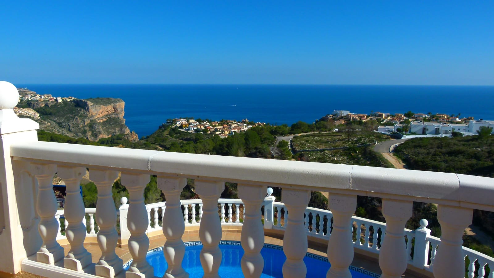 Vue depuis la terrasse avec balustrade blanche sur la piscine et la mer Méditerranée à Cumbre del Sol.