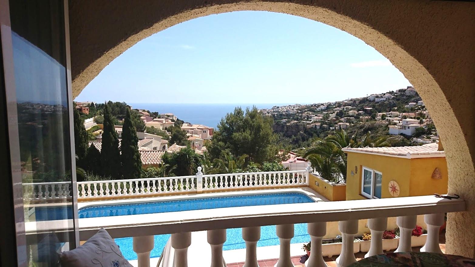 Vue depuis la naya encadrée par une arche, surplombant la piscine privée, la balustrade blanche et l'horizon marin de Cumbre del Sol.