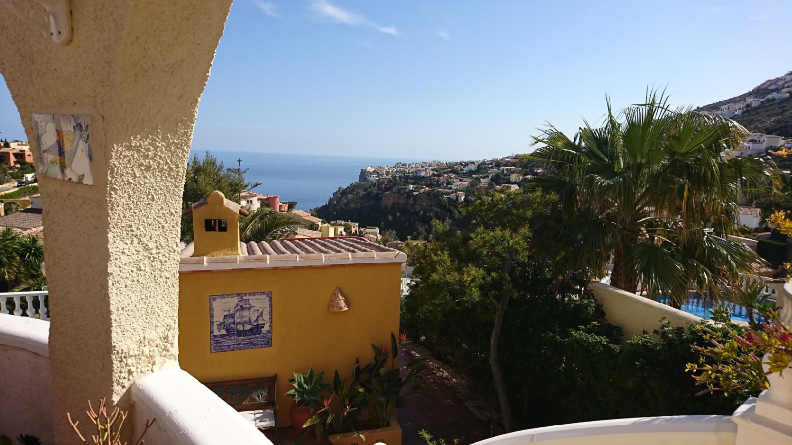 Vue panoramique sur la mer Méditerranée depuis la naya, soulignée par une arche traditionnelle, des azulejos décoratifs et un jardin arboré.