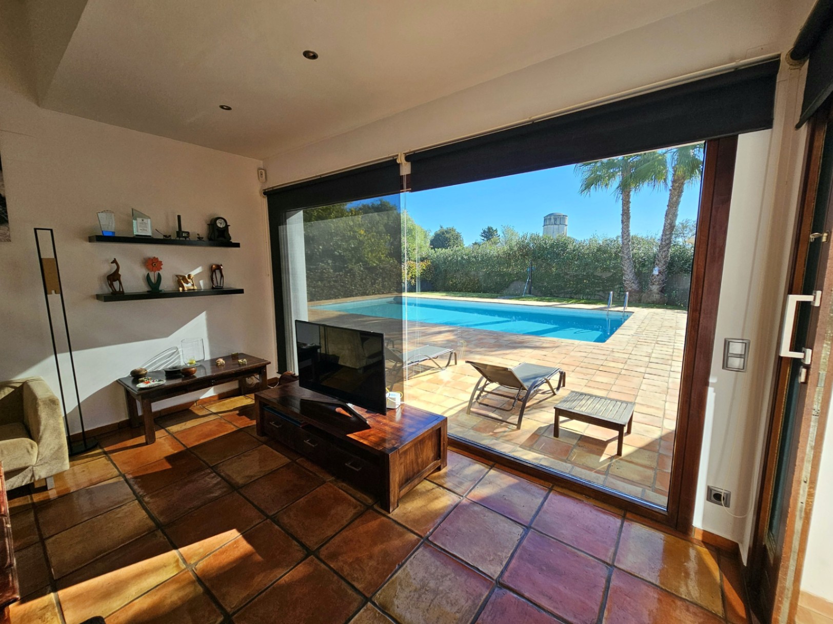 Espace de vie avec sol en terre cuite artisanale et larges baies vitrées s'ouvrant sur la terrasse ensoleillée et la piscine privée.