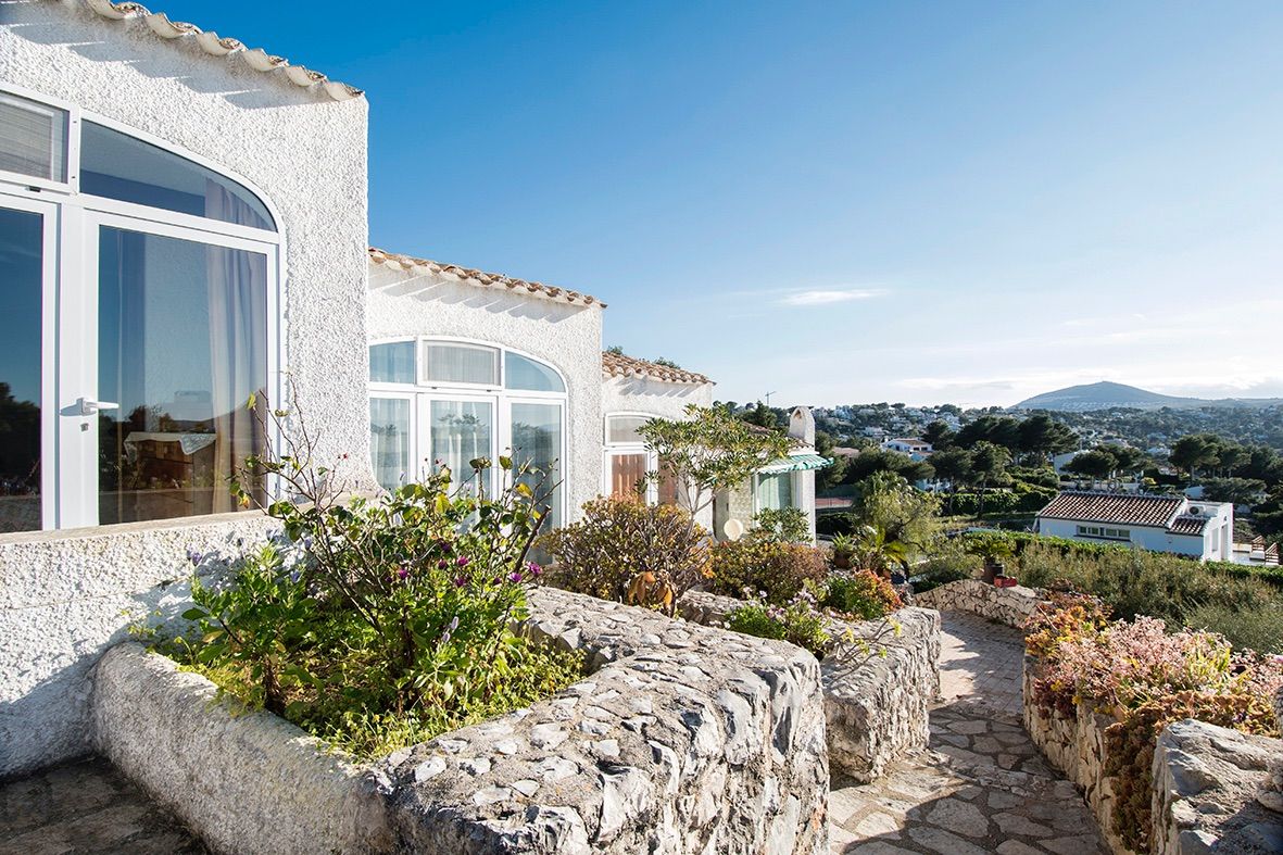 Extérieur de style traditionnel avec murs en pierre naturelle, fenêtres cintrées et chemin pavé offrant une vue panoramique sur la vallée et les montagnes.
