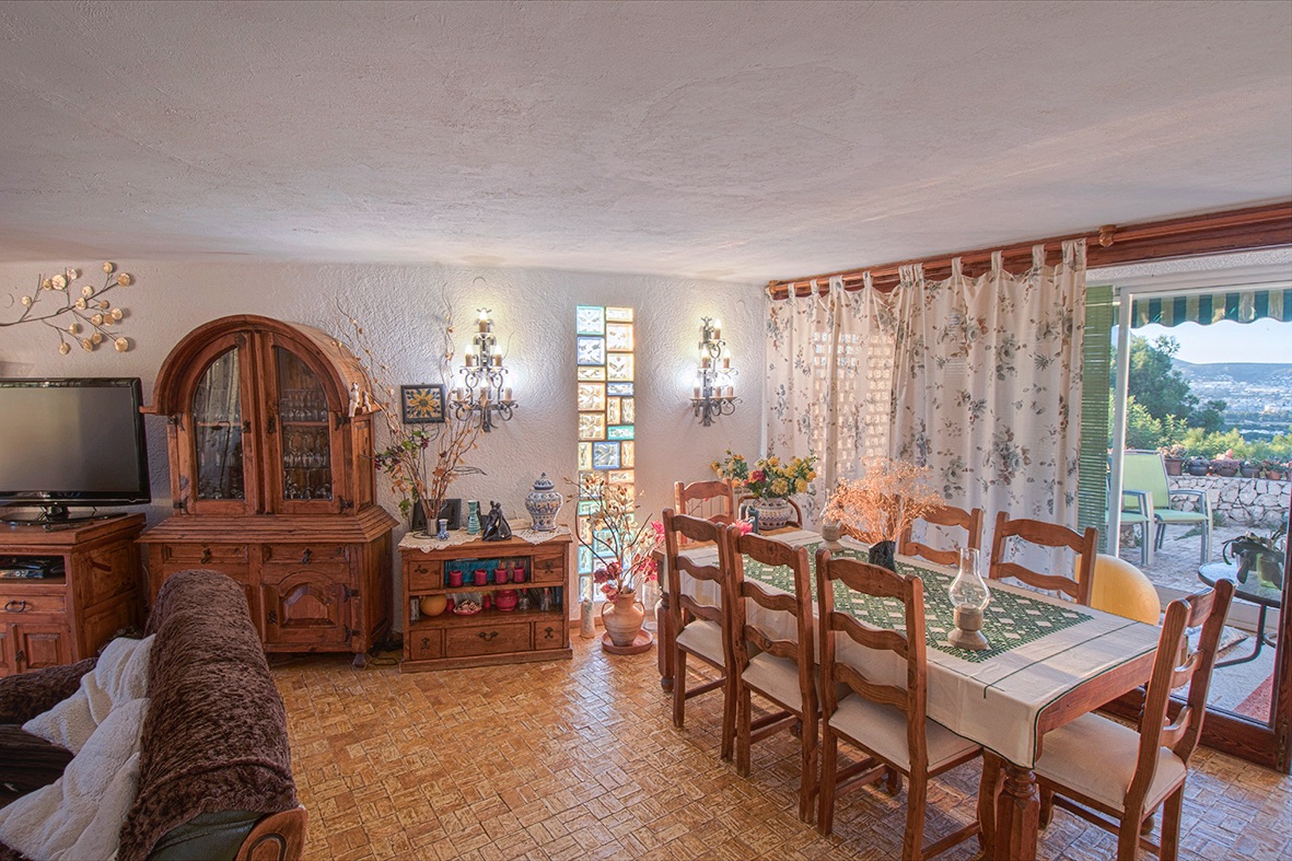 Salle à manger rustique avec meubles en bois traditionnels, sol en grès et accès direct à la terrasse offrant une vue dégagée sur la vallée environnante.