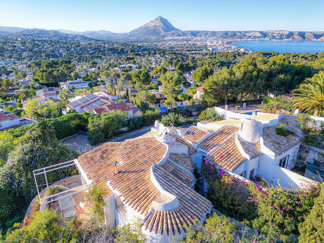 Vue aérienne de la villa traditionnelle aux toits de tuiles incurvés, offrant un panorama exceptionnel sur le Montgó et la baie de Jávea.