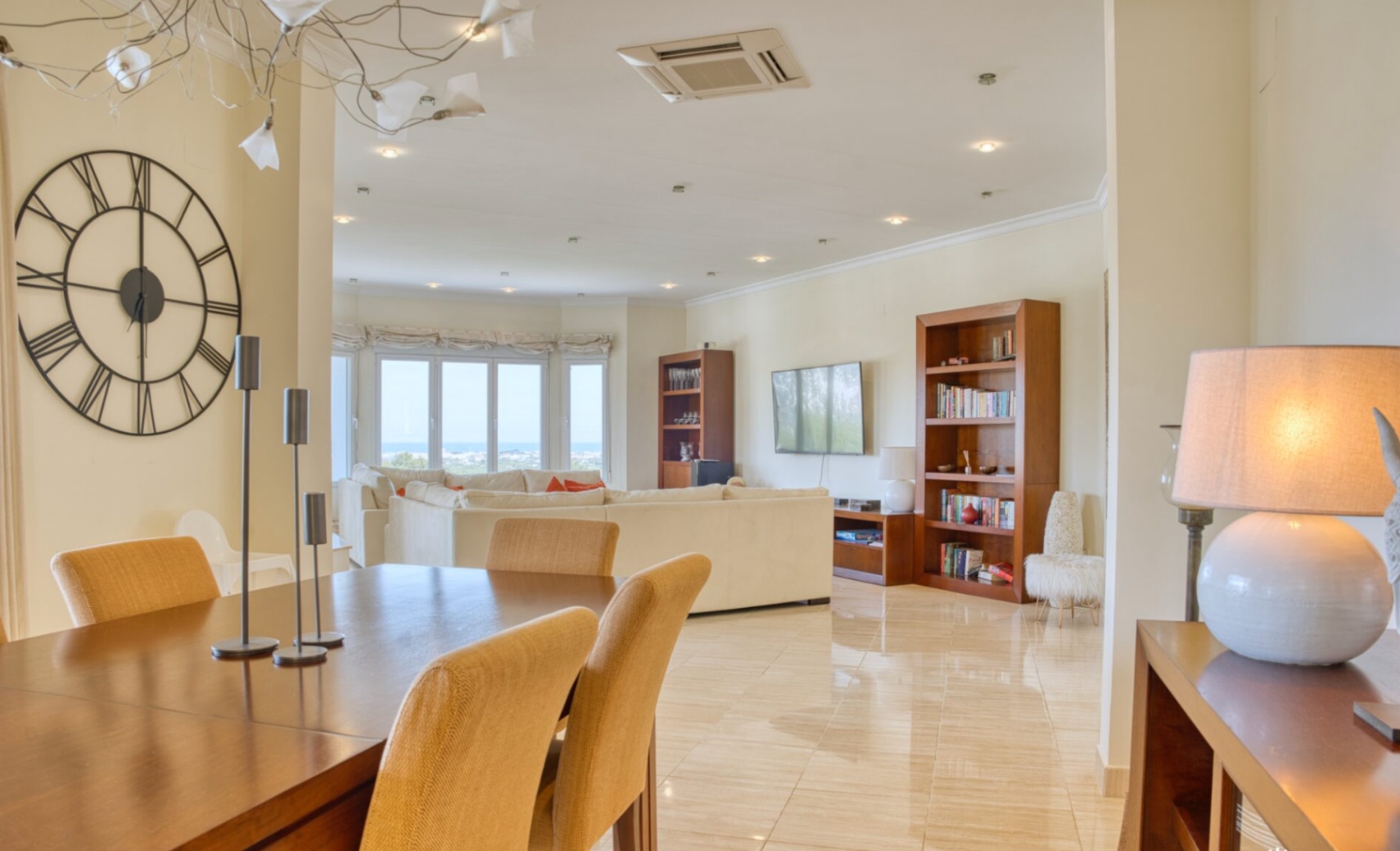 Salon-salle à manger à aire ouverte avec sols en marbre poli, mobilier en bois et grandes baies vitrées offrant une vue dégagée sur la mer Méditerranée.