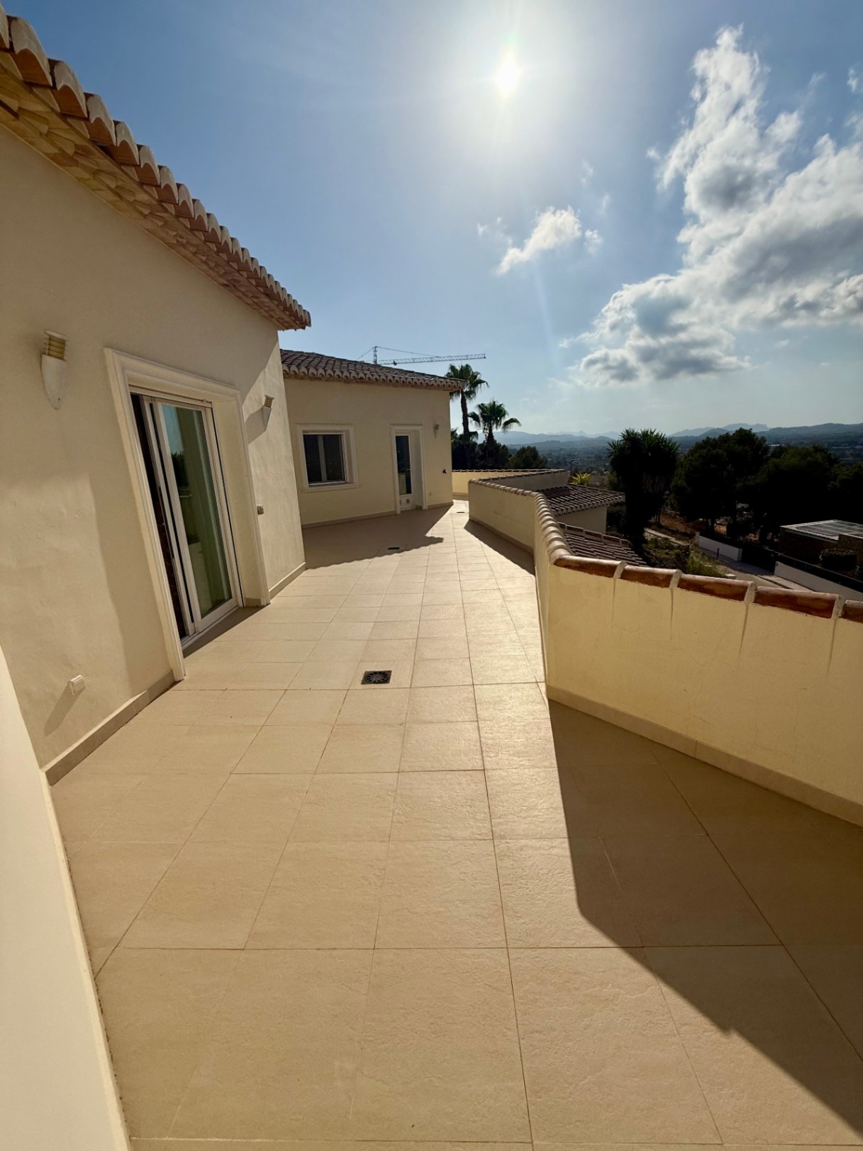 Vaste terrasse à l'étage avec revêtement en grès cérame, offrant une vue panoramique sur la vallée et les montagnes environnantes sous une lumière naturelle intense.