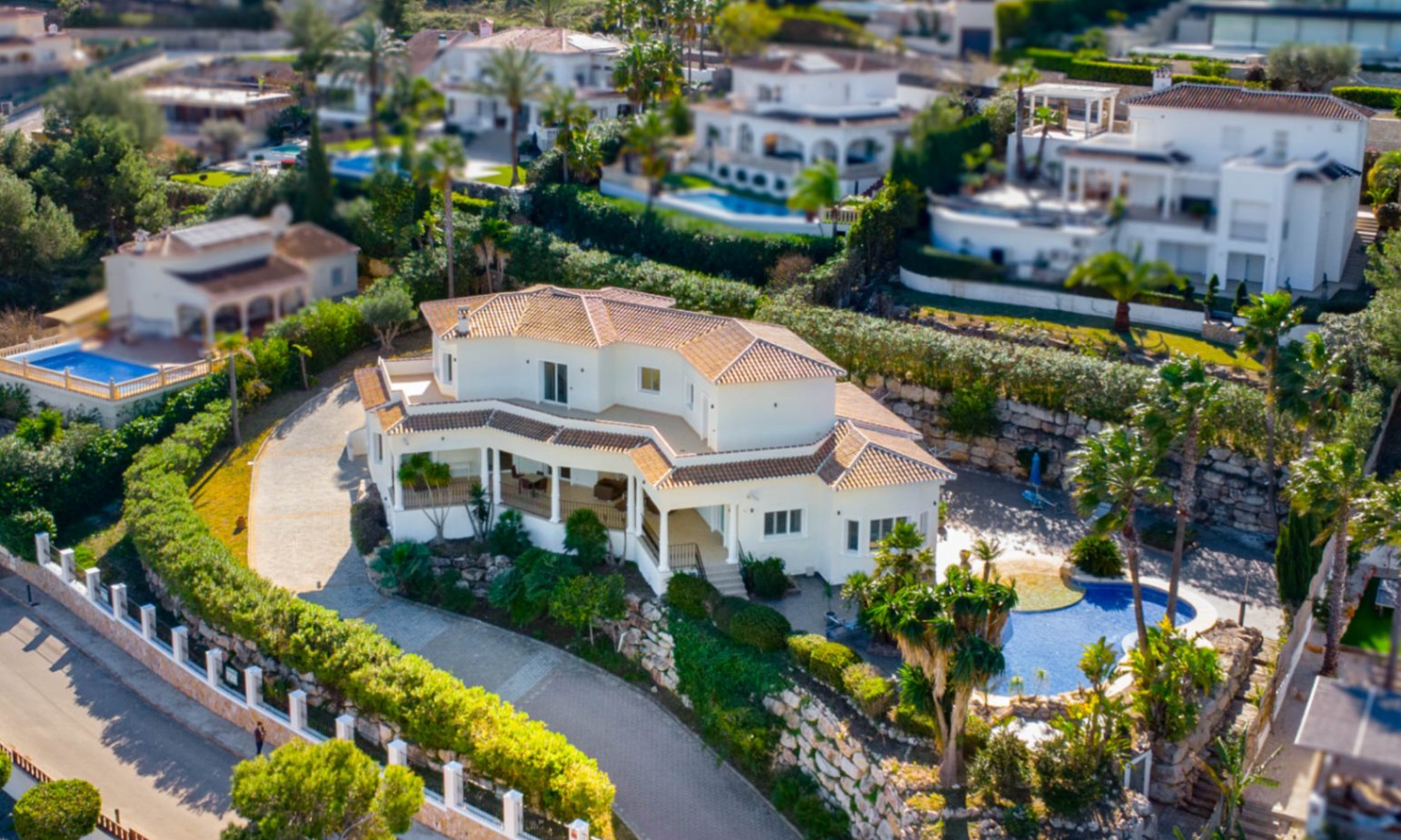 Vue aérienne de la villa à Piver, Jávea, illustrant son architecture méditerranéenne, ses toits en tuiles et sa piscine entourée d'un jardin paysager soigné.