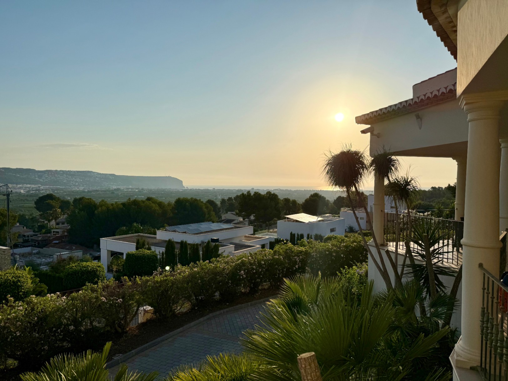 Vue panoramique au coucher du soleil depuis la terrasse supérieure, soulignant les colonnes blanches et l'horizon méditerranéen de Jávea.