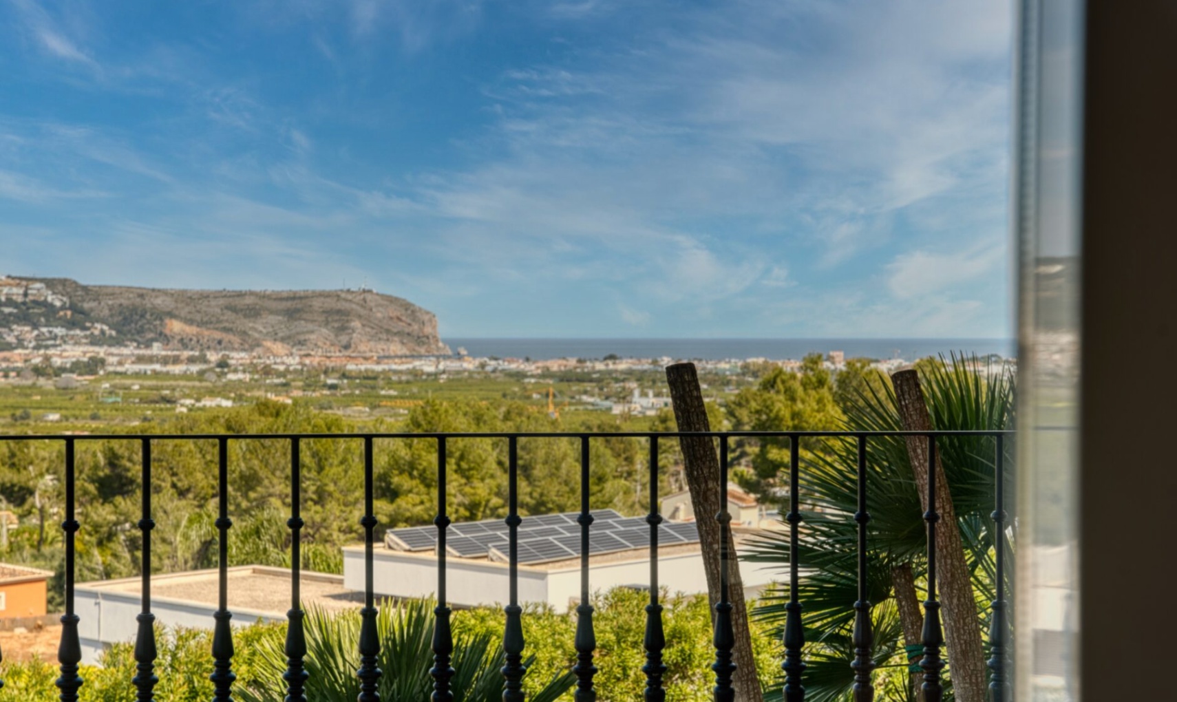 Vue panoramique depuis la terrasse avec garde-corps en fer forgé, offrant un panorama sur la mer Méditerranée et le cap San Antonio.